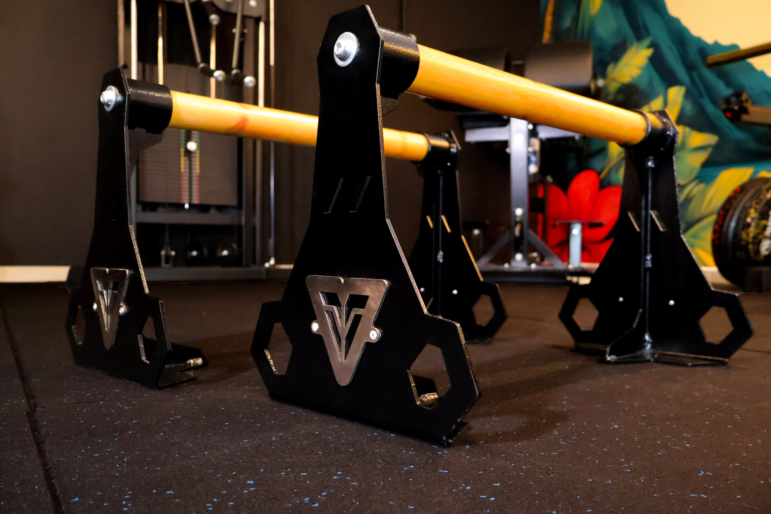 Veevon Wooden High Pro Parallettes with black steel frame, stainless steel logo and bright wooden handles on a gym rubber floor